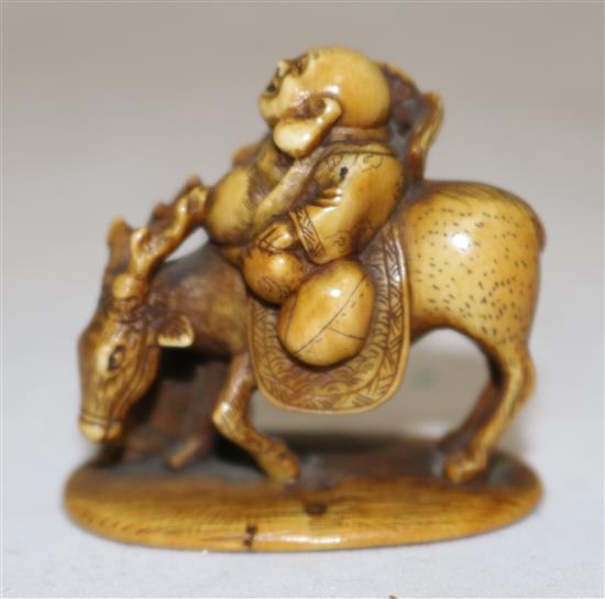 A Japanese stained ivory okimono netsuke of Hotei riding a deer, signed Tomochika, Meiji period, 4.1cm